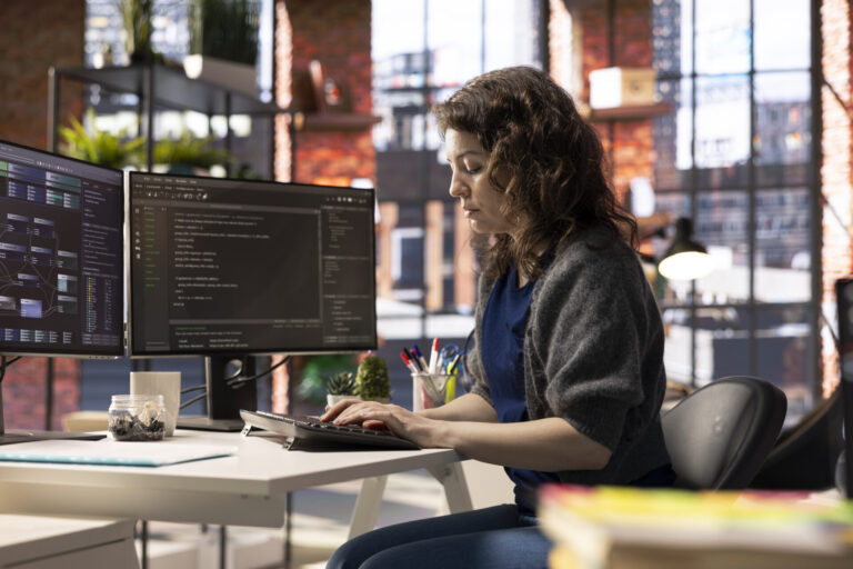 African american software engineer works on dual monitors and typing code
